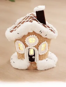 Close-up of cozy gingerbread house ornament with snowy roof and warm LED light effect