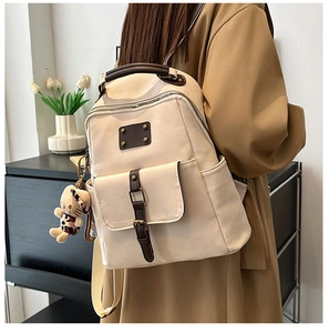 Detail of off-white faux leather backpack with brown handles and a cute dog charm