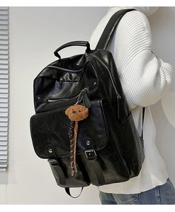 Side view of black PU leather backpack with vintage metal zippers and plush bear charm