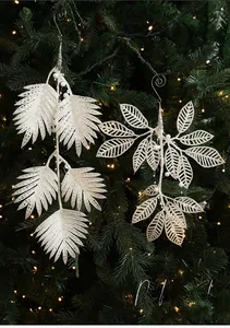 Gros plan d'ornements de feuilles de fougère blanches scintillantes sur un sapin