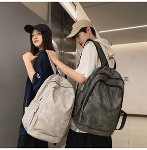 Side view of beige and charcoal large capacity travel backpacks worn by models