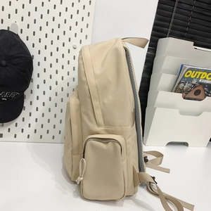 Side view of beige nylon backpack with mesh back padding and multi-pocket storage