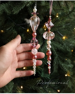Détail de décorations de Noël en acrylique rose suspendues à un sapin illuminé