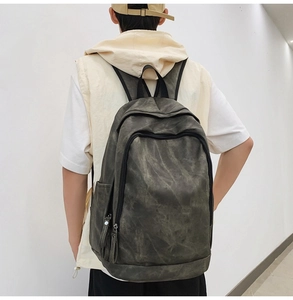 Back view of a casual dark grey backpack with vintage texture on a male model