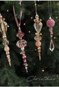 Gros plan de perles de cristal acrylique rose et pendentifs sur branches de sapin