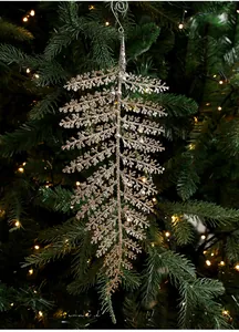 Détail de la feuille de fougère dorée pailletée avec boules argentées sur un sapin de Noël