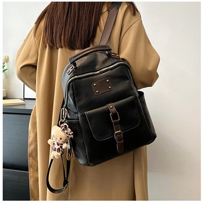 Detail view of a vintage black faux leather backpack on model wearing khaki coat