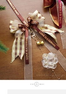 Detail of Christmas bow ornament with golden bells and crystal beads on wooden surface