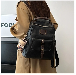 Detail of vintage black pebbled leather backpack with brown trim and metal buckle