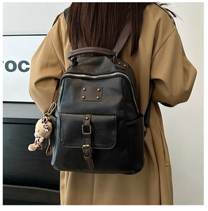Detailed back view of a black leather backpack with brown straps worn on a trench coat
