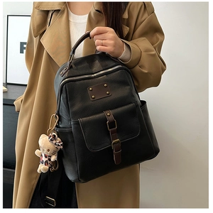 Detailed view of black faux leather backpack with side pocket and cute cat plush pendant