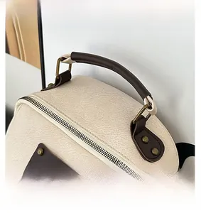 Detail of off-white lychee grain leather backpack with brown handle and bronze hardware