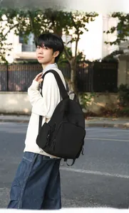 Outdoor view of a black minimalist nylon backpack with multiple zippered pockets
