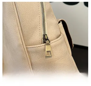 Close-up of vintage bronze zipper and textured litchi grain leather on beige backpack