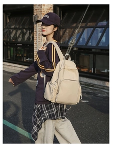 Detailed side view of a beige minimalist backpack featuring adjustable straps and pockets