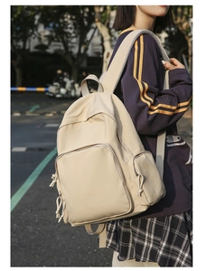 Outdoor view of beige nylon school backpack featuring multiple pockets and durable straps