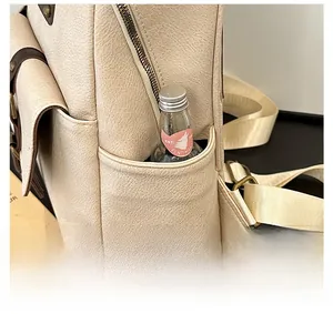 Detail of off-white PU leather backpack featuring side pocket and bronze hardware