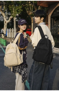 Outdoor lifestyle shot of two models wearing minimalist nylon backpacks in beige and black