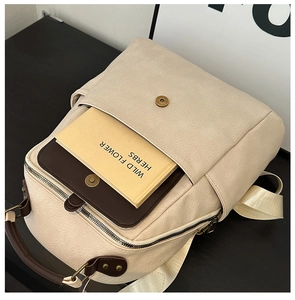 Close-up of beige leather backpack detail with vintage buckle and front pocket for books