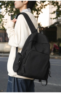 Side view of black minimalist backpack with multiple utility pockets and wide padded straps