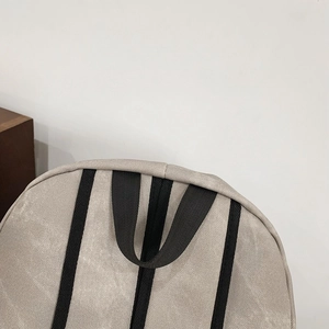 Detail of reinforced top handle and woven texture on this beige laptop backpack