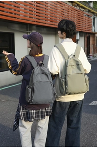 Detailed outdoor view of two spacious nylon backpacks in dark grey and sage green colors