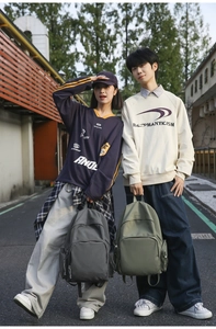 Outdoor street style shot of models carrying large capacity nylon backpacks in grey and green