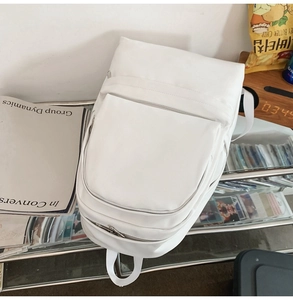 Close-up of minimalist white waterproof backpack with multi-zipper compartments and pockets