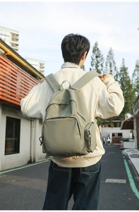 Detail view of bean green nylon backpack with front pocket and zippered side pockets