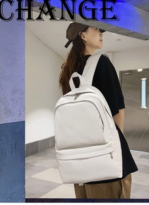 Detail view of a white minimalist backpack for women with zippered pockets on stylish model