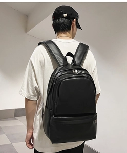 Detailed view of the matte black synthetic leather backpack shown on female model