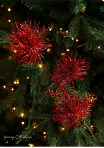 Close-up of red glitter Christmas floral picks on a festive tree with warm lights