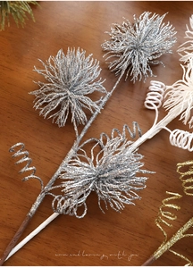 Close-up of sparkling silver glitter dandelion stem with spiral wires on wood