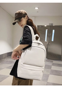 Detailed side view of a minimalist white canvas backpack with spacious zipper pockets