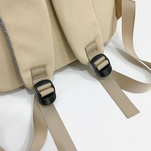 Detailed close-up of durable nylon shoulder strap stitching and buckle on beige backpack