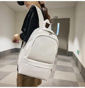 Detailed side view of white minimalist backpack on model showing strap and size
