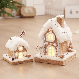 Lighted Christmas gingerbread house set with fake snow and warm LED lights on wood