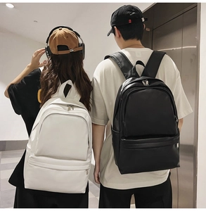 Rear view of minimalist black and white leather backpacks on models in a public space