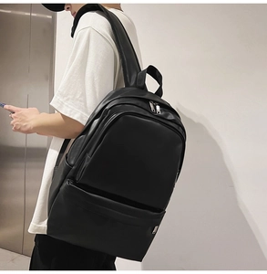Side view of sleek black leather backpack showing shoulder straps and minimalist design