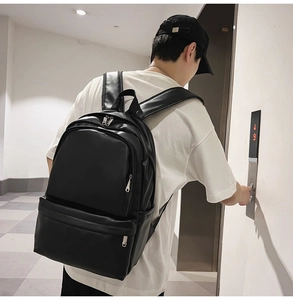 Detailed view of the black leather backpack with wide adjustable shoulder straps on model