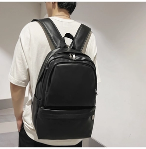 Detail view of stylish black PU leather backpack with silver zippers on a female model