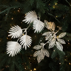 Feuilles de Noël blanches avec paillettes et perles sur une branche scintillante