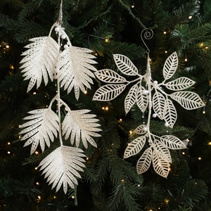 Feuille de fougère pailletée blanche et branche de perles sur un sapin de Noël