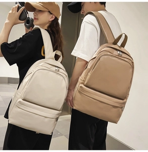 Detail of minimalist cream and khaki leather backpack shown on models in a city style