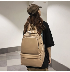 Detail view of large capacity khaki leather backpack with front zipper and side pocket