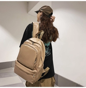 Detailed view of beige leather backpack with multi-pocket design on female model