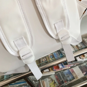 Detail of padded adjustable shoulder straps and white buckles on a minimalist backpack