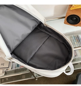 Interior view of white minimalist backpack showing spacious main compartment and grey lining