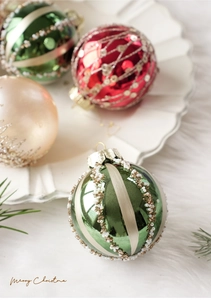 Dettaglio di palline di Natale da 8cm con trama di perle su un vassoio di ceramica bianca