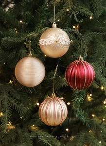 Dettaglio di palline di Natale rosse e champagne con paillettes sui rami dell'albero